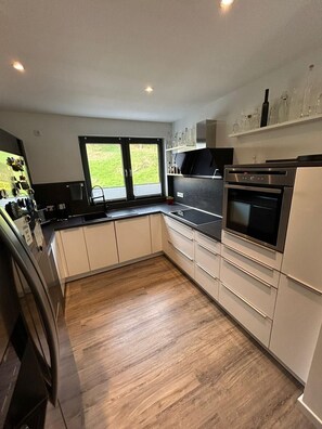 A modern kitchen with a built-in oven, a black countertop, and wooden flooring. - Vacation Home A30 Balitherme Spa Park Heart Clinic Monteur Apartment GOP Modern (Bad Oeynhausen)