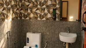 Un bagno con servizi igienici, bidet e lavandino, caratterizzato da piastrelle a motivi geometrici e una finestra.