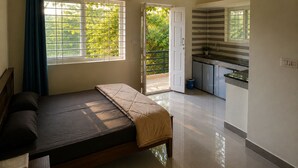 Una camera da letto con un letto, una finestra con tende e vista su un paesaggio verde.