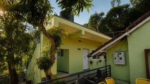 Un edificio verde con un portico coperto, posti a sedere all'aperto e una scala che conduce all'ingresso.