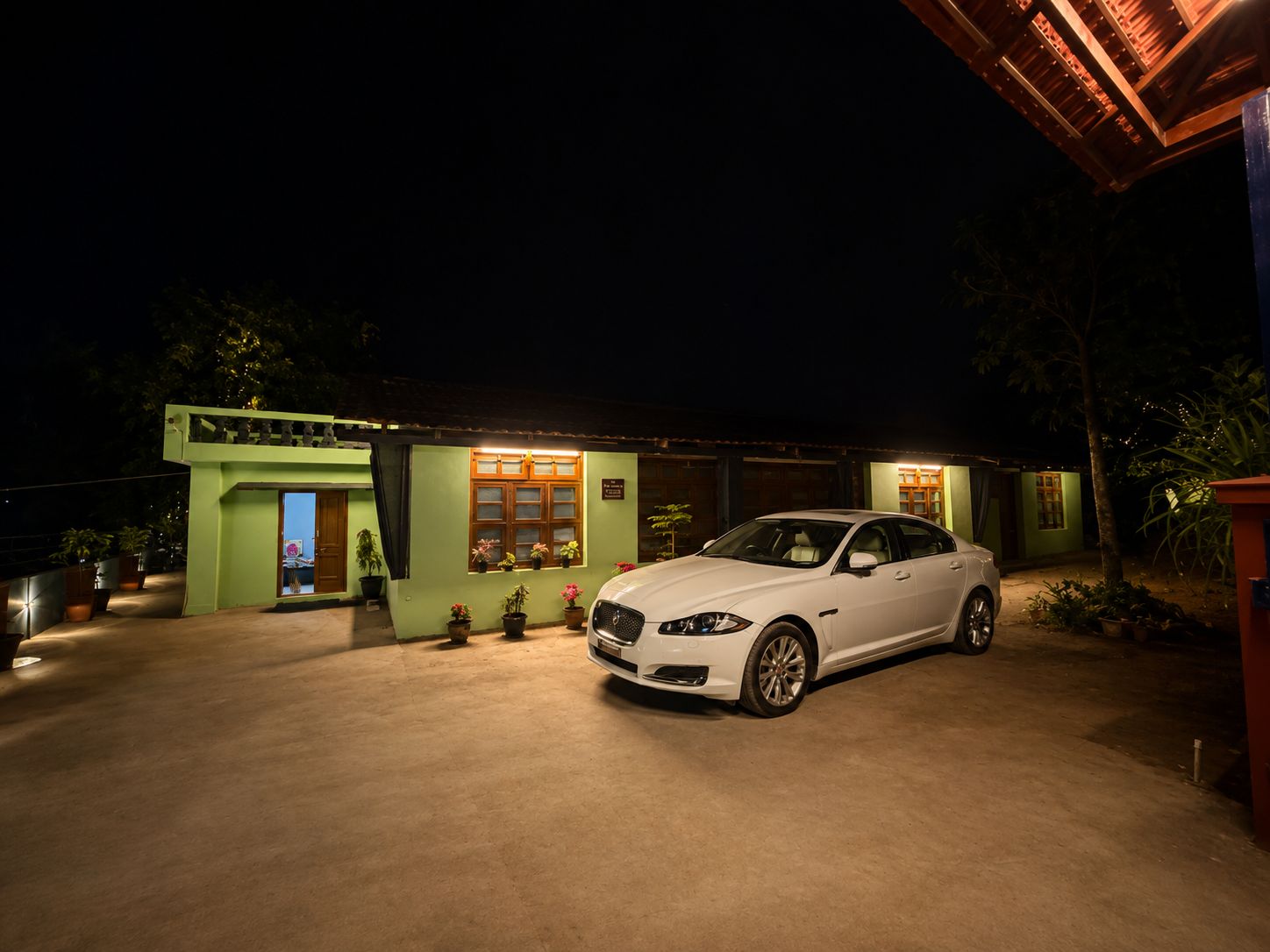 A white car parked in front of a house with a green facade and a covered porch.