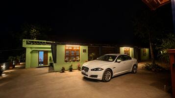A white car parked in front of a house with a green facade and a covered porch.
