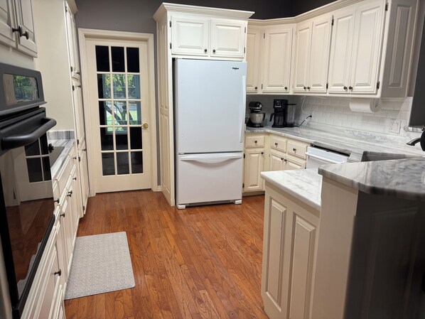 A kitchen with white cabinetry, a built-in refrigerator, a microwave, and a coffee maker.