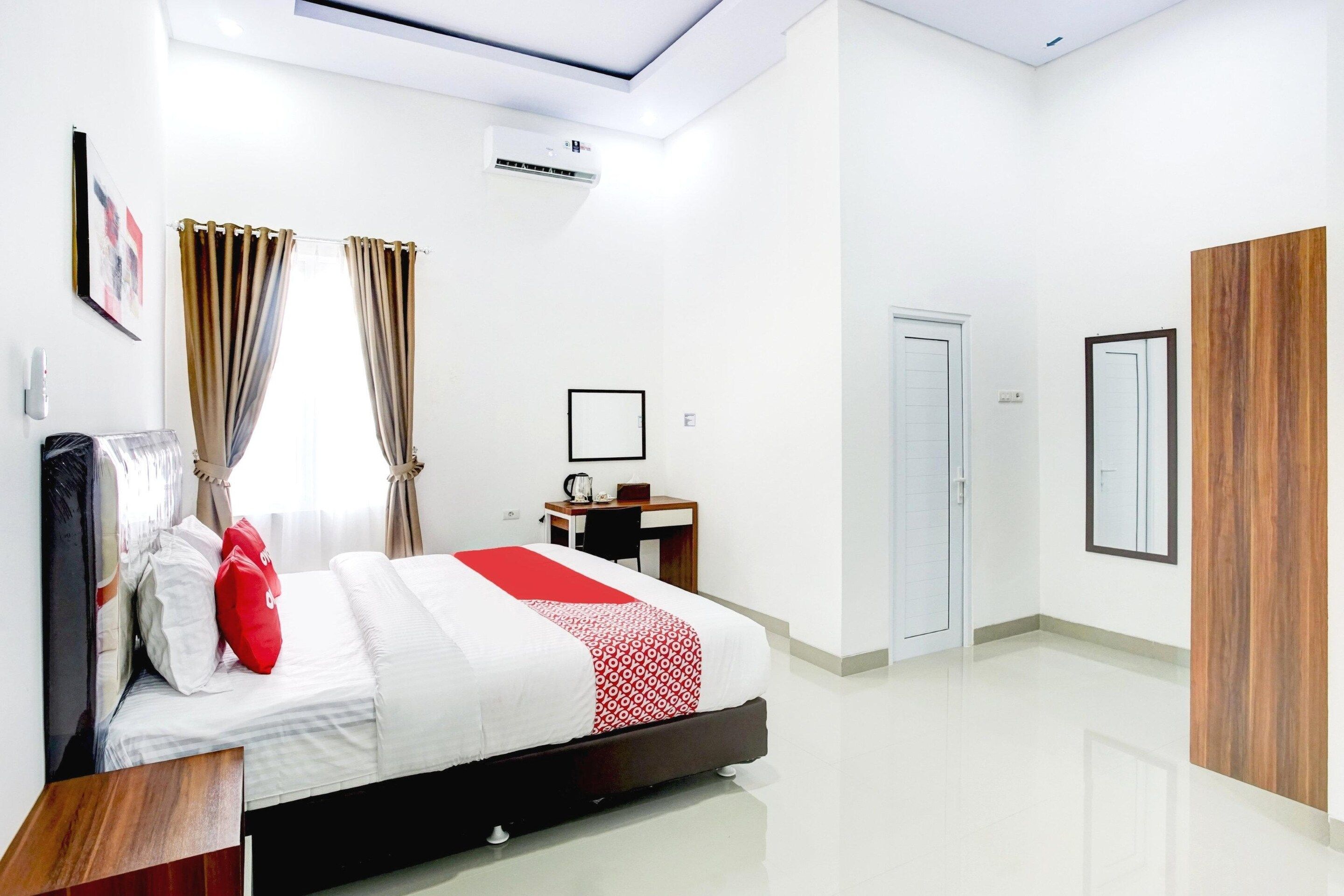 A hotel room with a bed, a desk, a wardrobe, and a door.