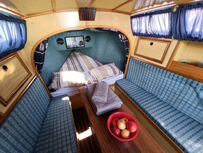 Un intérieur chaleureux avec un lit, deux coins salon et une table sur laquelle se trouve un bol de pommes.