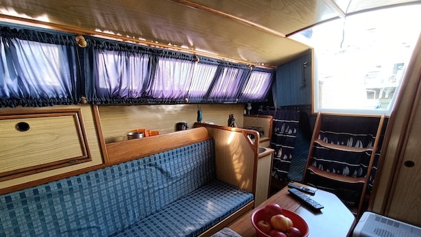 Un espacio habitable compacto con sofá, una mesita con un frutero, televisión y ventana con cortinas.