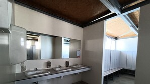 Baño con tres lavamanos, un espejo y un banco.