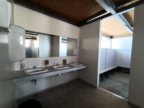 Des toilettes équipées de trois lavabos, d’un miroir et d’un banc.
