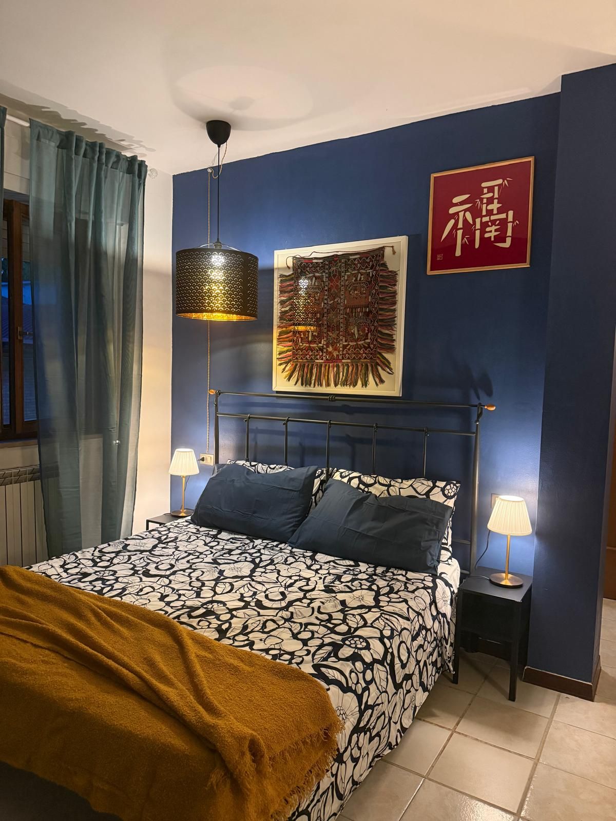 Una camera da letto con un letto, due lampade da comodino, un'opera d'arte appesa al muro e un cartello rosso.