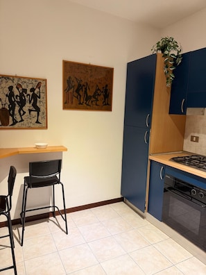 A kitchen with a stove, oven, and a dining area with chairs. - Just a Stone's Throw Away – Cozy Apartment with Parking in Grosseto (Grosseto)