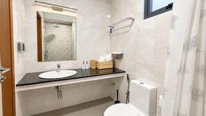 Un baño moderno con lavabo, espejo, inodoro y ducha.