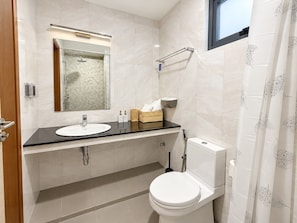 Un baño moderno con lavabo, espejo, inodoro y ducha.