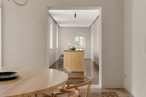 A spacious room with a wooden dining table and chairs, a kitchen area with a central island, and a view through an arched doorway. - Historic Baroque Palazzo w/Rooftop Terrace, City (Modica)