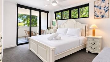 A bedroom with a bed, a nightstand, a lamp, a chair, a mirror, and a sliding glass door leading to an outdoor area.