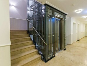 Ein modernes Interieur mit einem Glastreppenlift, einer Treppe und einem Flur.