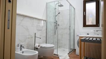 Ein Badezimmer mit Duschkabine, Toilette, Bidet und Waschbecken.