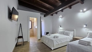A hotel room with two beds, a flat-screen TV, and a wooden ceiling. - Borgo Caridà - Green Family Holidays (Zaccanopoli)