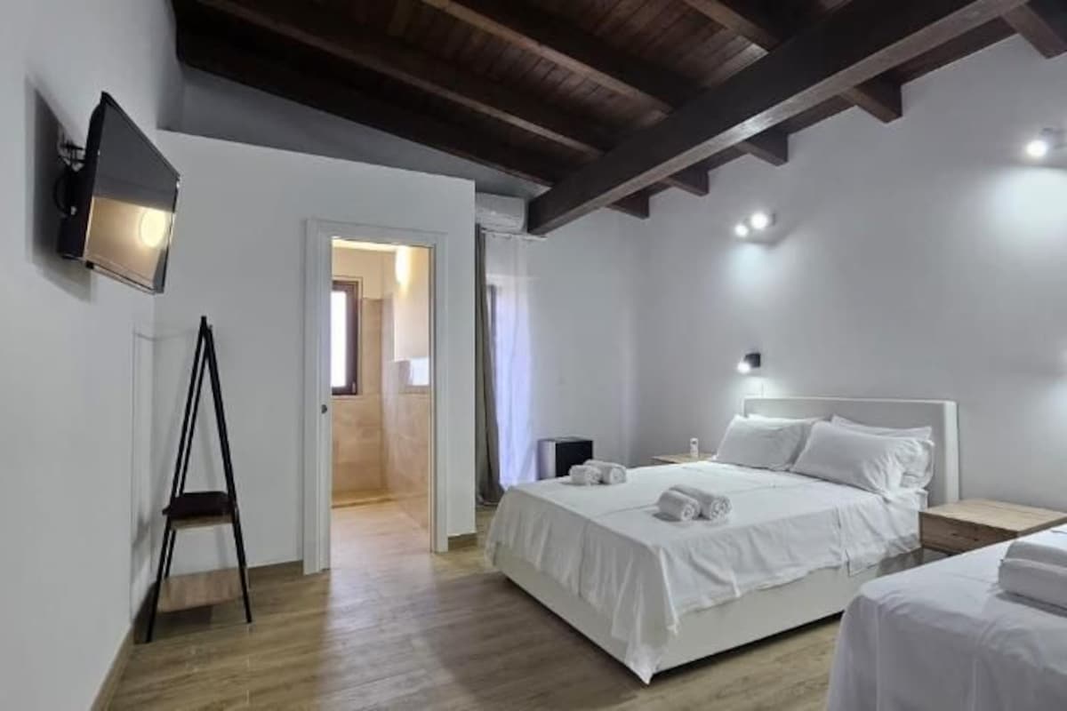 Habitación de hotel con dos camas, un televisor de pantalla plana y techo de madera.