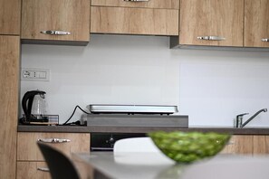 A kitchen with wooden cabinets, a coffee maker, a microwave, and a sink. - Borgo Caridà - Green Family Holidays (Zaccanopoli)
