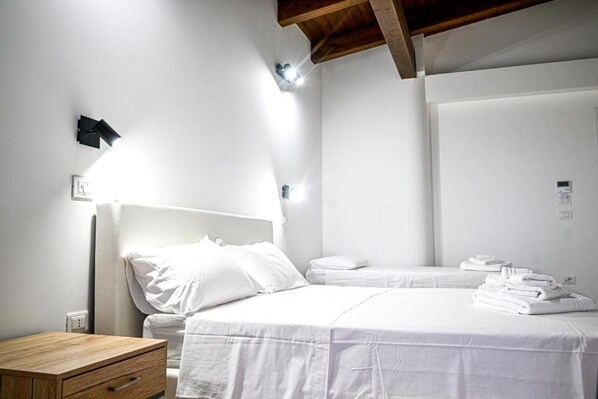 A hotel room with a bed, bedside table, and a wall-mounted light fixture.