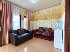 Una sala de estar con un sofá marrón, un sofá rojo y un refrigerador blanco.