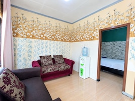 Una habitación con sofá, dispensador de agua y cama adosada a una pared de piedra.
