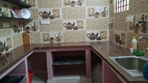 Una cocina con salpicadero de azulejos que muestra teteras, un fregadero y una encimera.