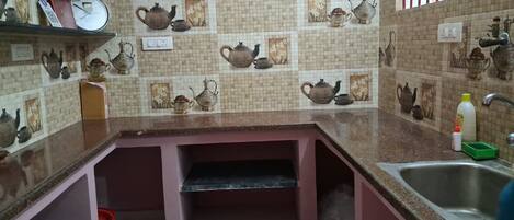 A kitchen with a tiled backsplash featuring teapots, a sink, and a countertop.