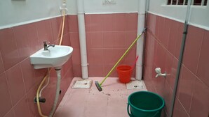 Un baño pequeño con lavamanos, un trapeador y un cubo.