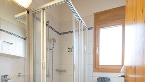 Une salle de bain avec une douche à parois de verre, un lavabo blanc et des toilettes.