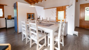 Un coin repas avec une table et des chaises en bois, un luminaire suspendu et une fenêtre donnant sur un beau paysage.