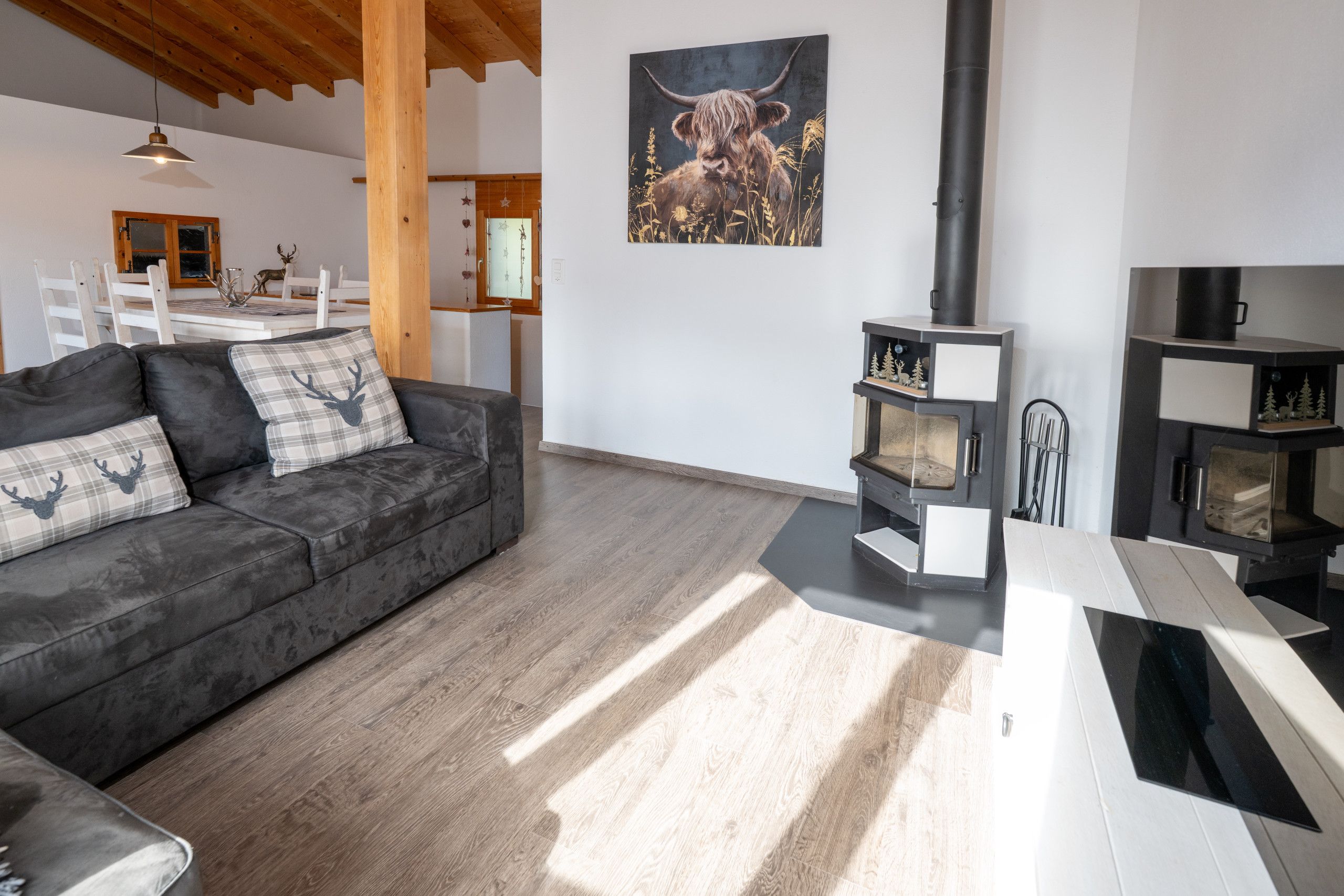 A modern living room with a dark grey sofa, a fireplace, and a dining area in the background.