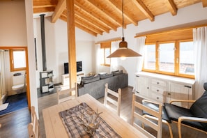 A modern interior with a dining area, a sofa, and a kitchen. - Malix: Apartment with Fireplace & Mountain View (Malix)
