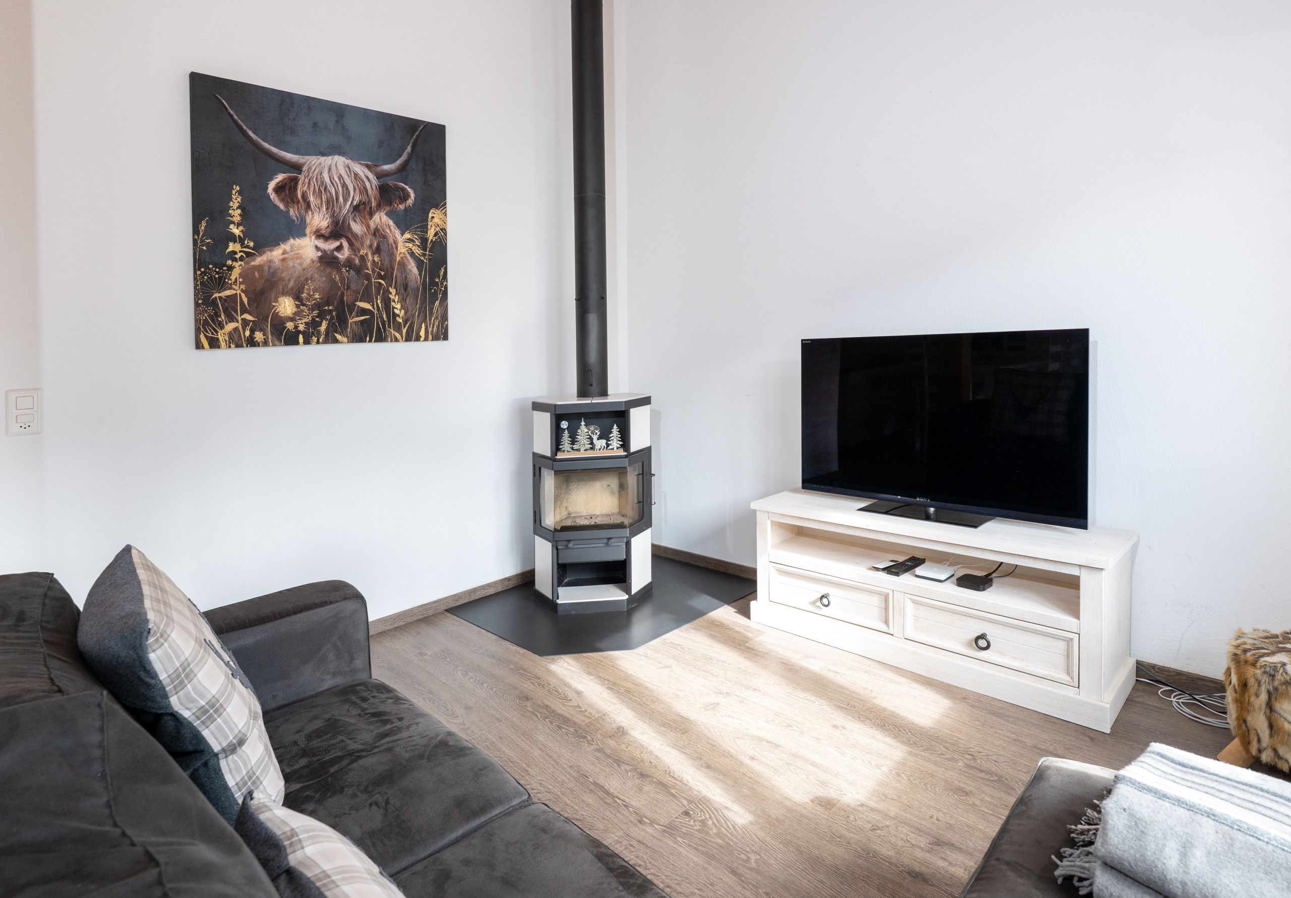 A living room with a sofa, a TV on a stand, a fireplace, and a painting on the wall.