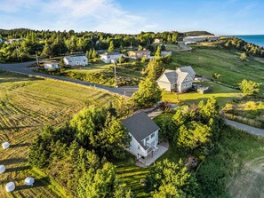 A residential area with houses, a large field, and a body of water in the background.