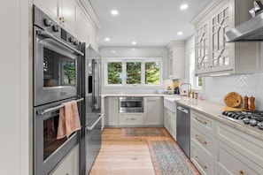 Una cucina moderna con elettrodomestici in acciaio inox, mobili bianchi e una finestra che si affaccia sul verde.