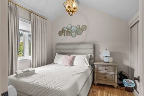 Una camera da letto con un letto, un comodino, una lampada e uno specchio fissato al muro.