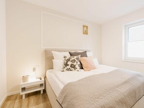 Un dormitorio con cama, mesita de noche y ventana.