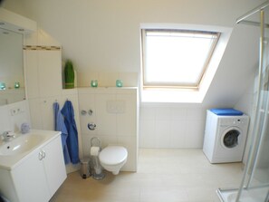 Ein kleines, sauberes Badezimmer mit Toilette, Waschbecken und Waschmaschine.