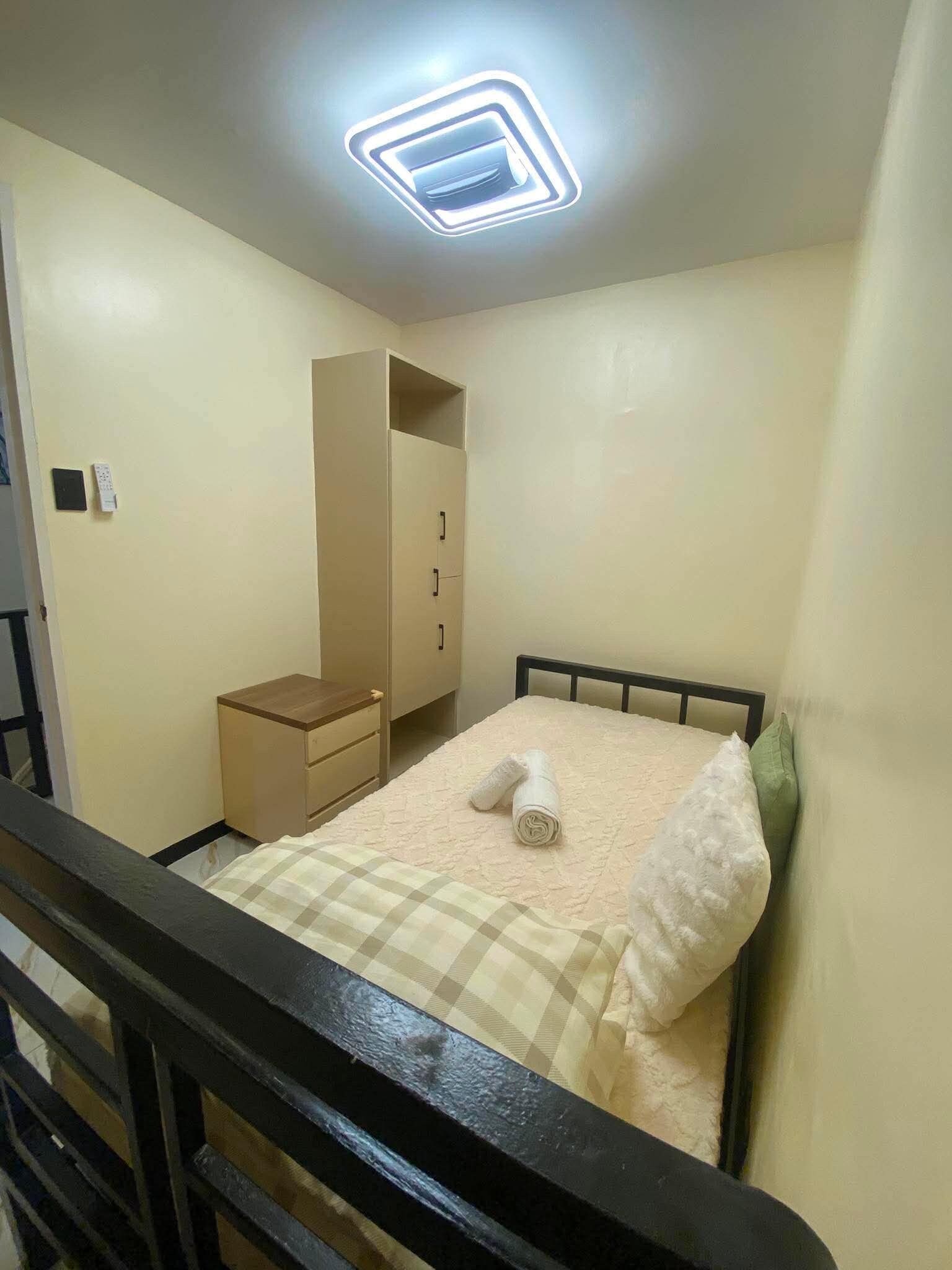 Une chambre à coucher comprenant un lit, une table de chevet, une armoire et un luminaire au plafond.