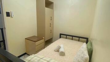 Une chambre à coucher comprenant un lit, une table de chevet, une armoire et un luminaire au plafond.