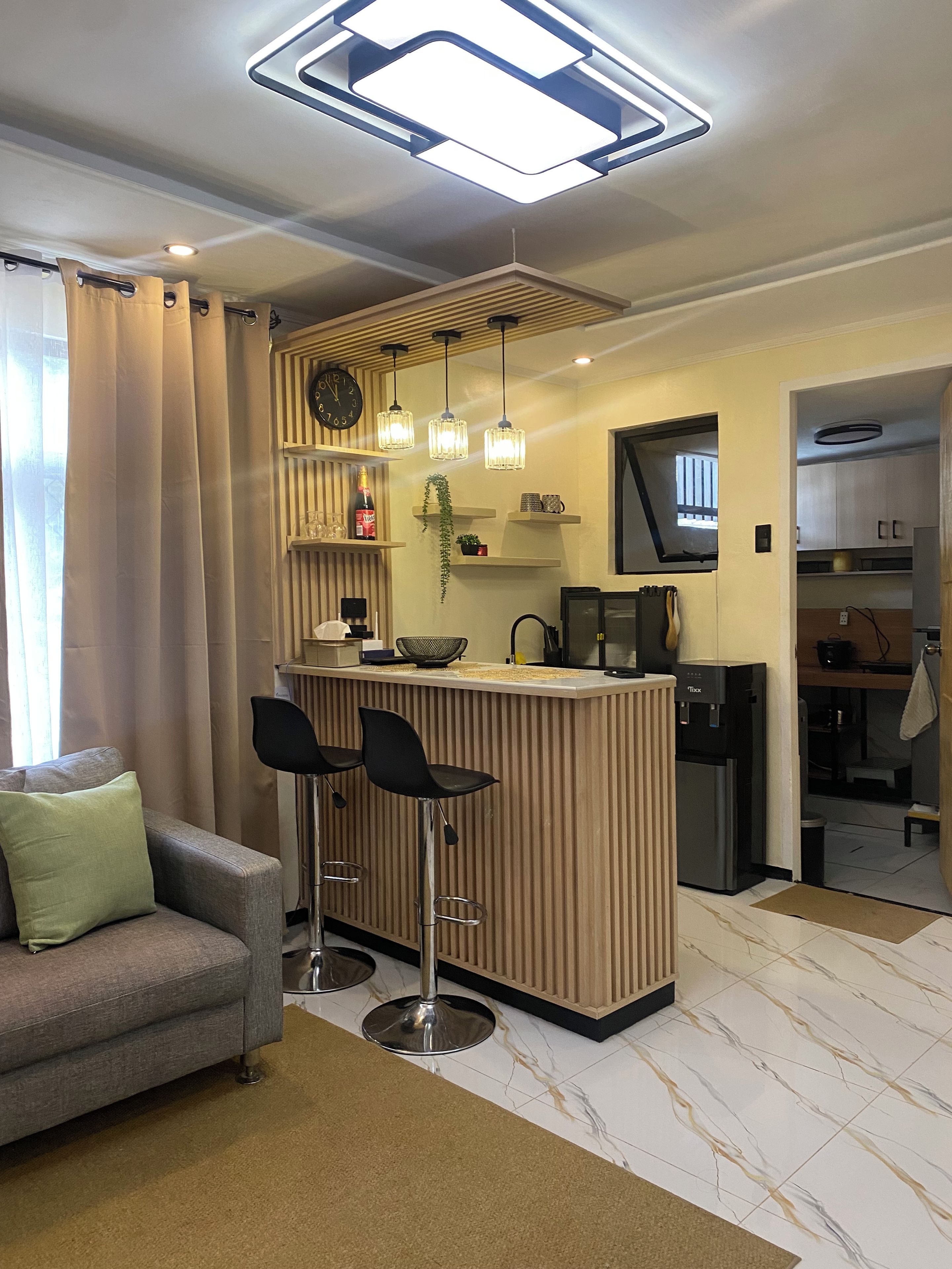 A modern kitchen with a bar area, a sofa, and a television.