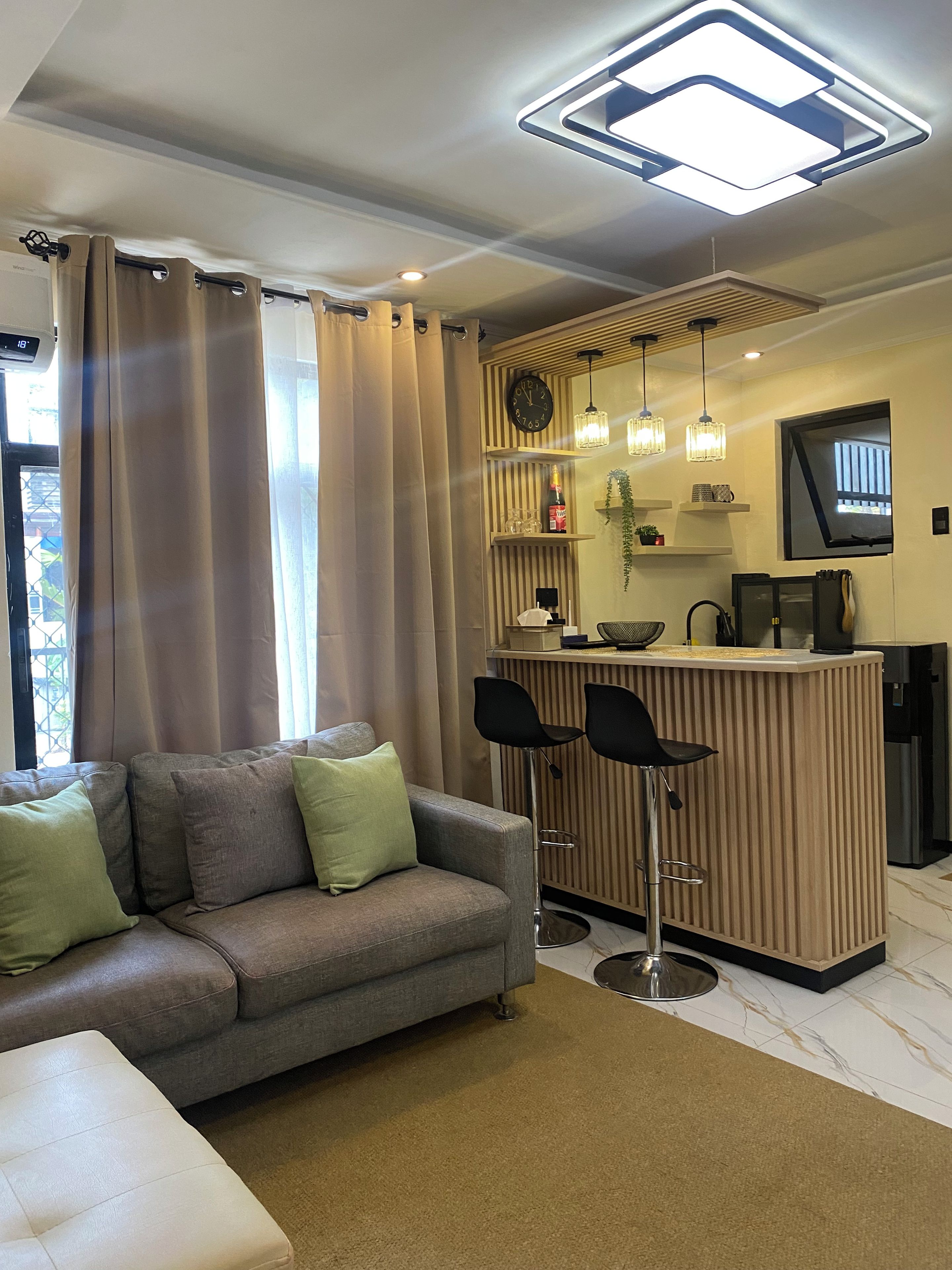 A modern living room with a sofa, a coffee table, and a bar area with stools.