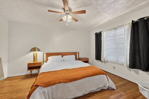 A bedroom with a bed, a nightstand, a lamp, a ceiling fan, and a window with curtains. - 3BR Near White Rock Lake - Fire Pit BBQ Grill (Dallas)