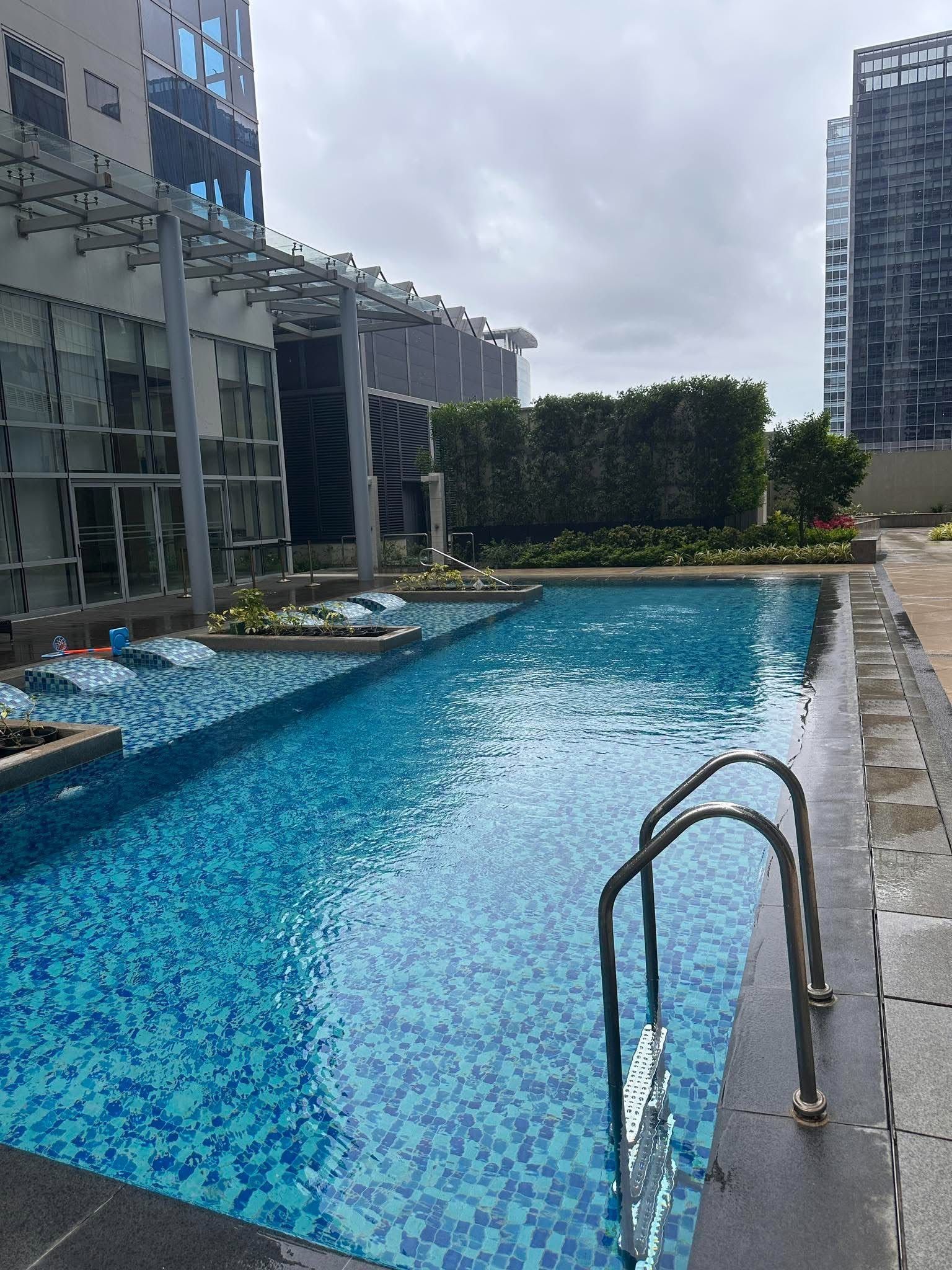 A swimming pool with a tiled deck and a metal ladder.