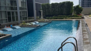 A swimming pool with a tiled deck and a metal ladder.