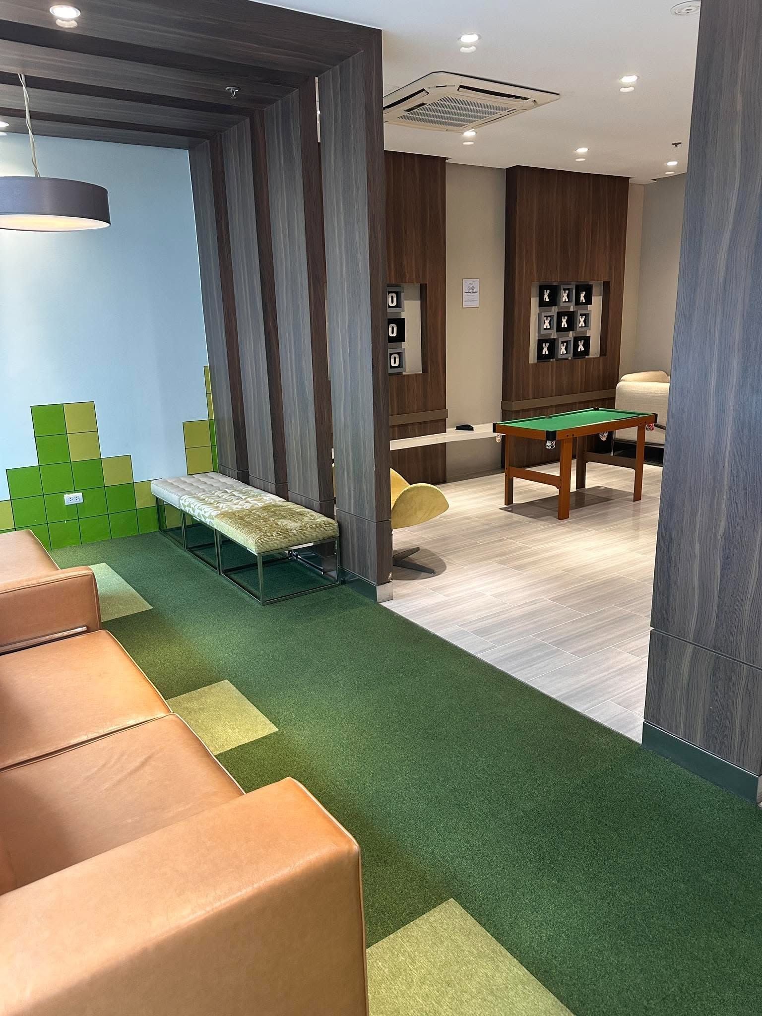 Una habitación con mesa de billar, un banco y una alfombra verde.