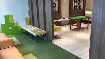Una habitación con mesa de billar, un banco y una alfombra verde.