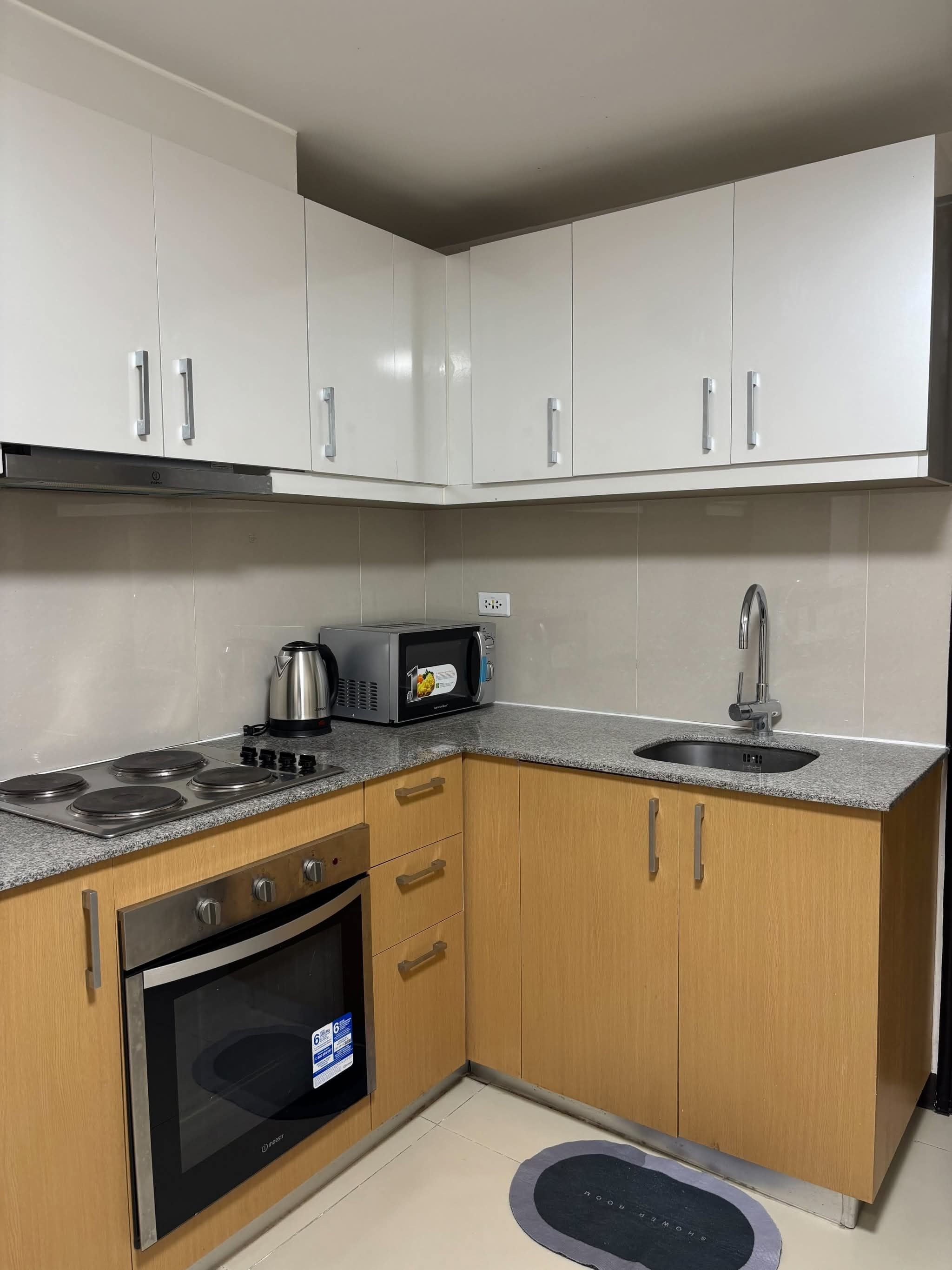 Una cocina moderna con armarios blancos, horno empotrado, microondas y estufa a gas.