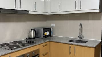 Una cocina moderna con armarios blancos, horno empotrado, microondas y estufa a gas.